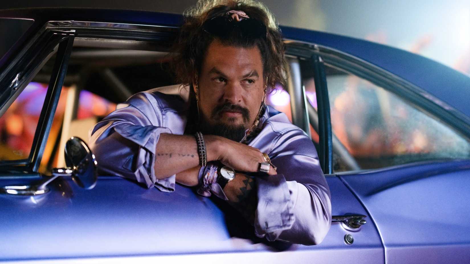 Jason Momoa in Fast X leaning out of the window of a purple car