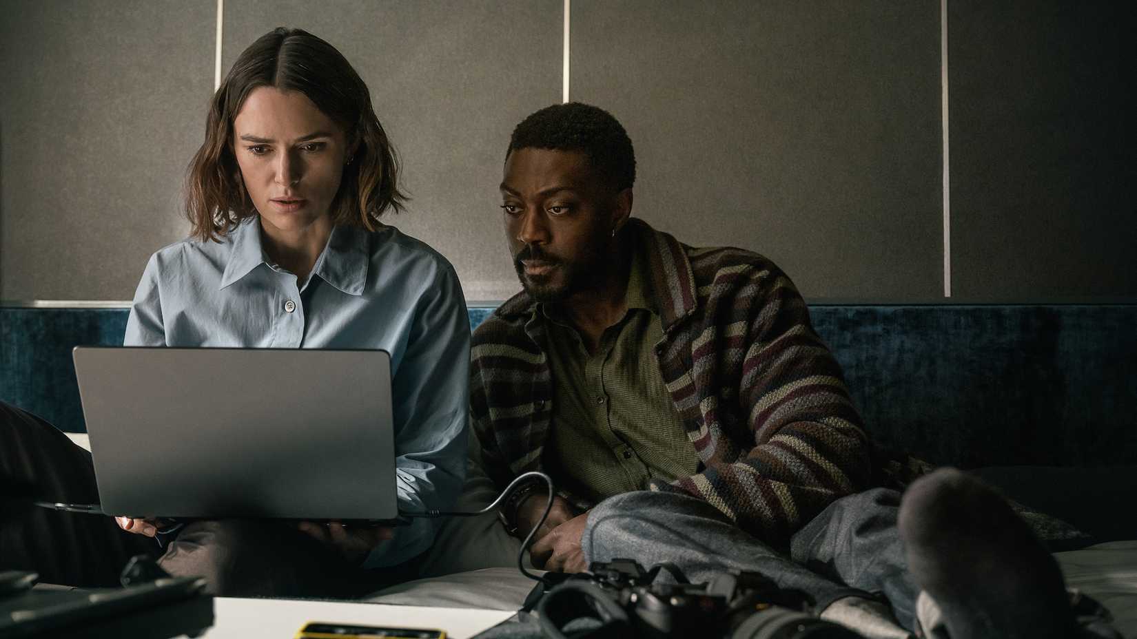 Keira Knightley and David Ajala looking at a laptop in The Woman in Cabin 10