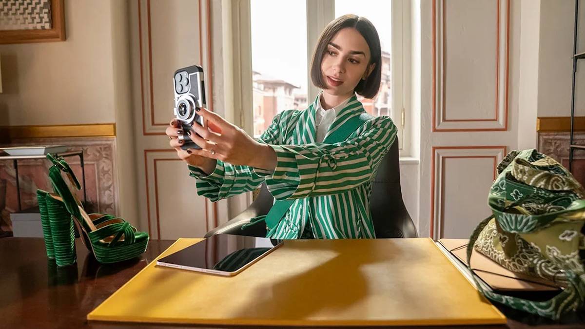 Lily Collins' Emily Cooper holding up her cell phone in Emily in Paris Season 5