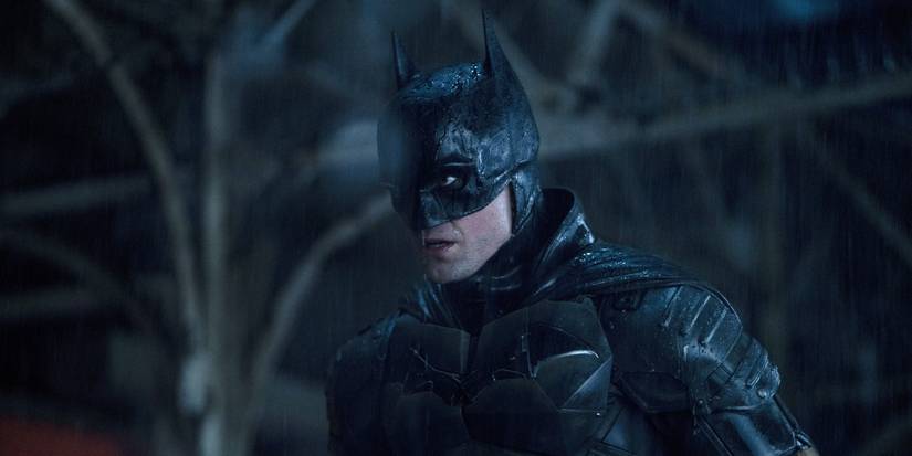 Robert Pattinson as Batman in The Batman in his costume standing in the rain