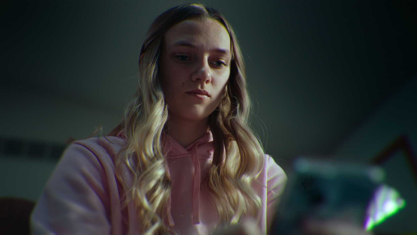 Lauryn staring at her phone in Unknown Number: The High School Catfish.