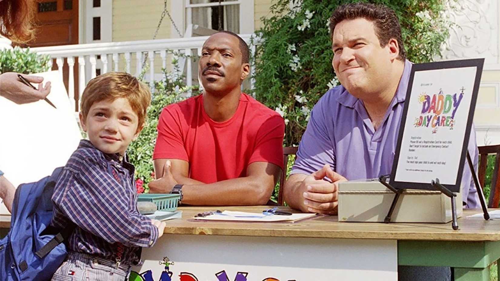 Two men behind a desk outside with a child in front of them in Daddy Day Care.