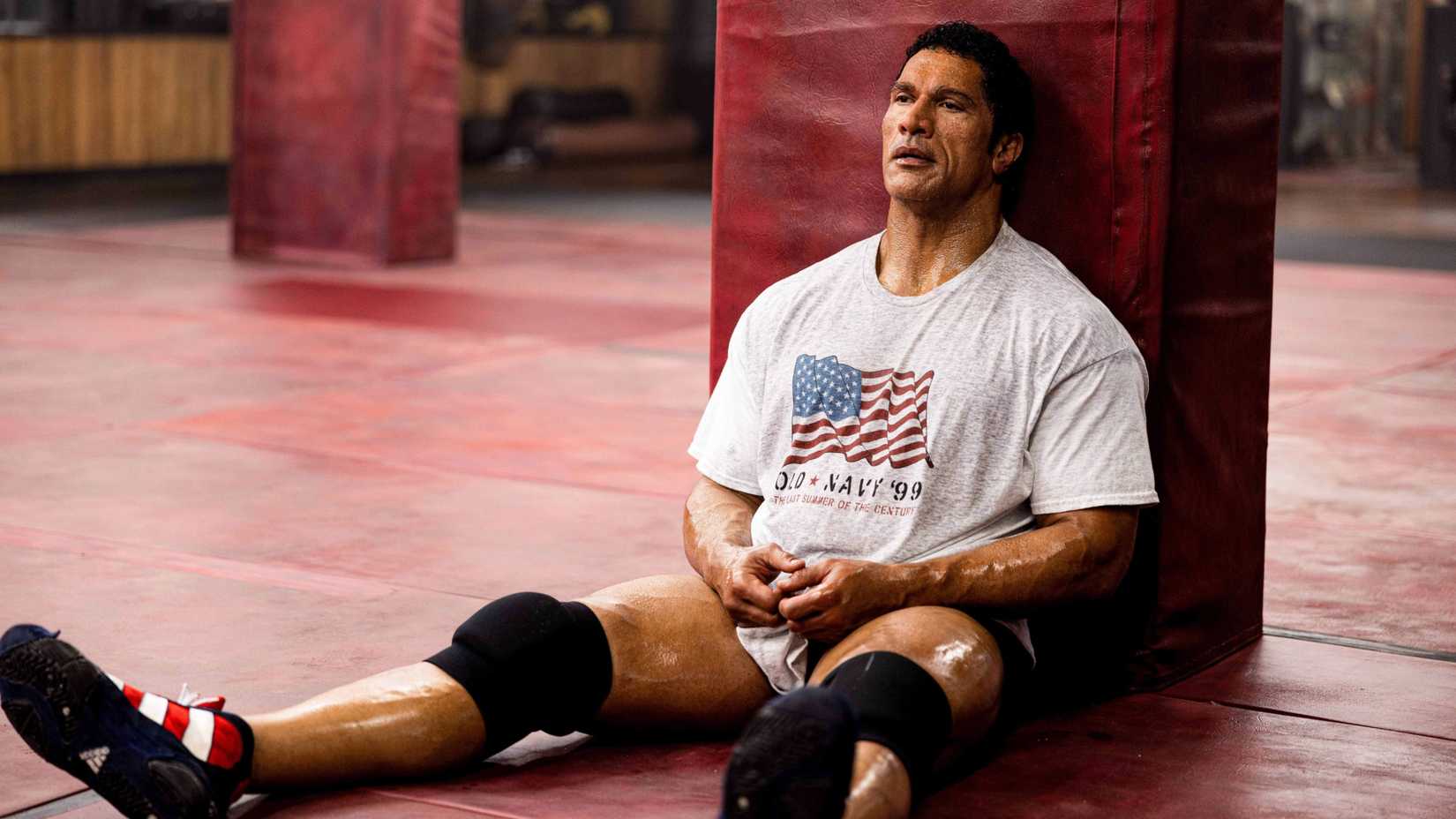 Dwayne Johnson in The Smashing Machine sitting down wearing training gear
