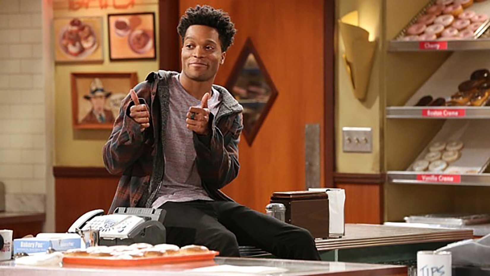 Jermaine Fowler sitting on a counter showing two thumbs up in Superior Donuts.