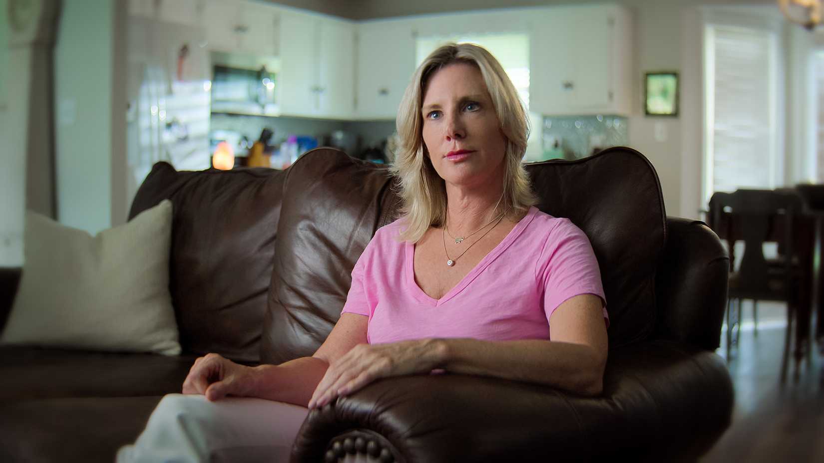 Jill Schardein sitting on a couch in a pink shirt being interviewed in Love Con Revenge.