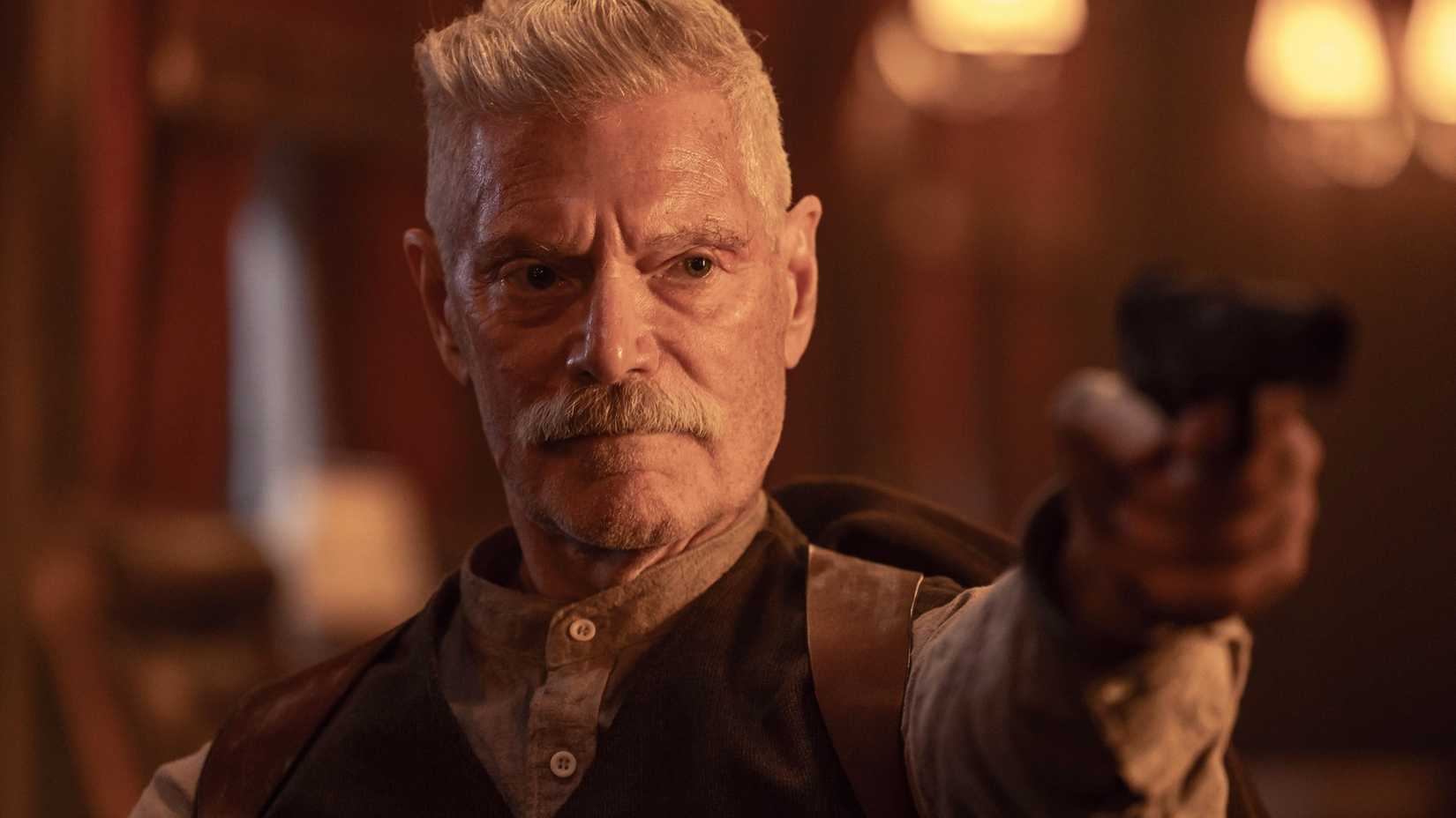 Stephen Lang in Sisu: Road to Revenge aiming a gun at someone off-screen