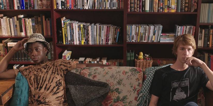 Earl (RJ Cyler) and Greg (Thomas Mann) sit on a couch in Me and Earl and the Dying Girl (2015)