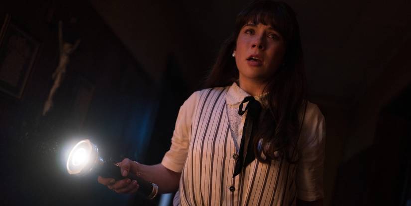 Mia Tomlinson holds a flashlight and looks scared in The Conjuring: Last Rites