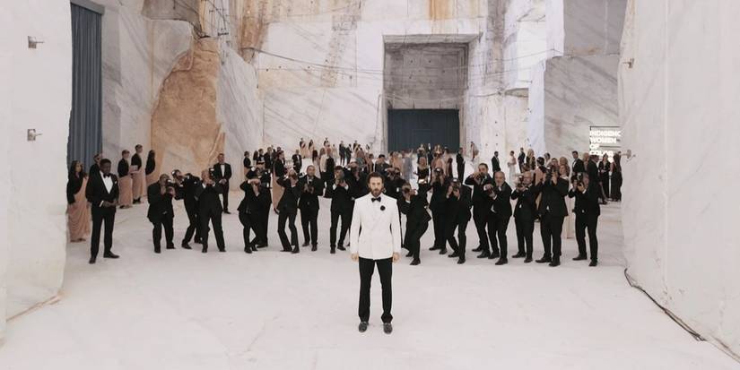 Chris Evans in Sacrifice wearing a tuxedo with people in suits behind him