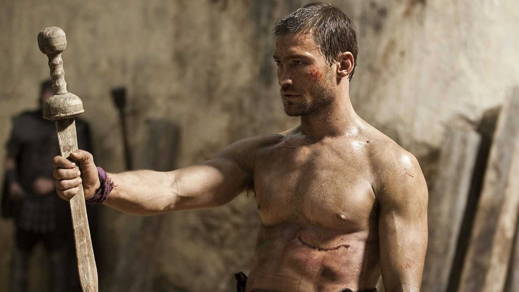 Spartacus holds a sword in Spartacus with cuts and blood on his body