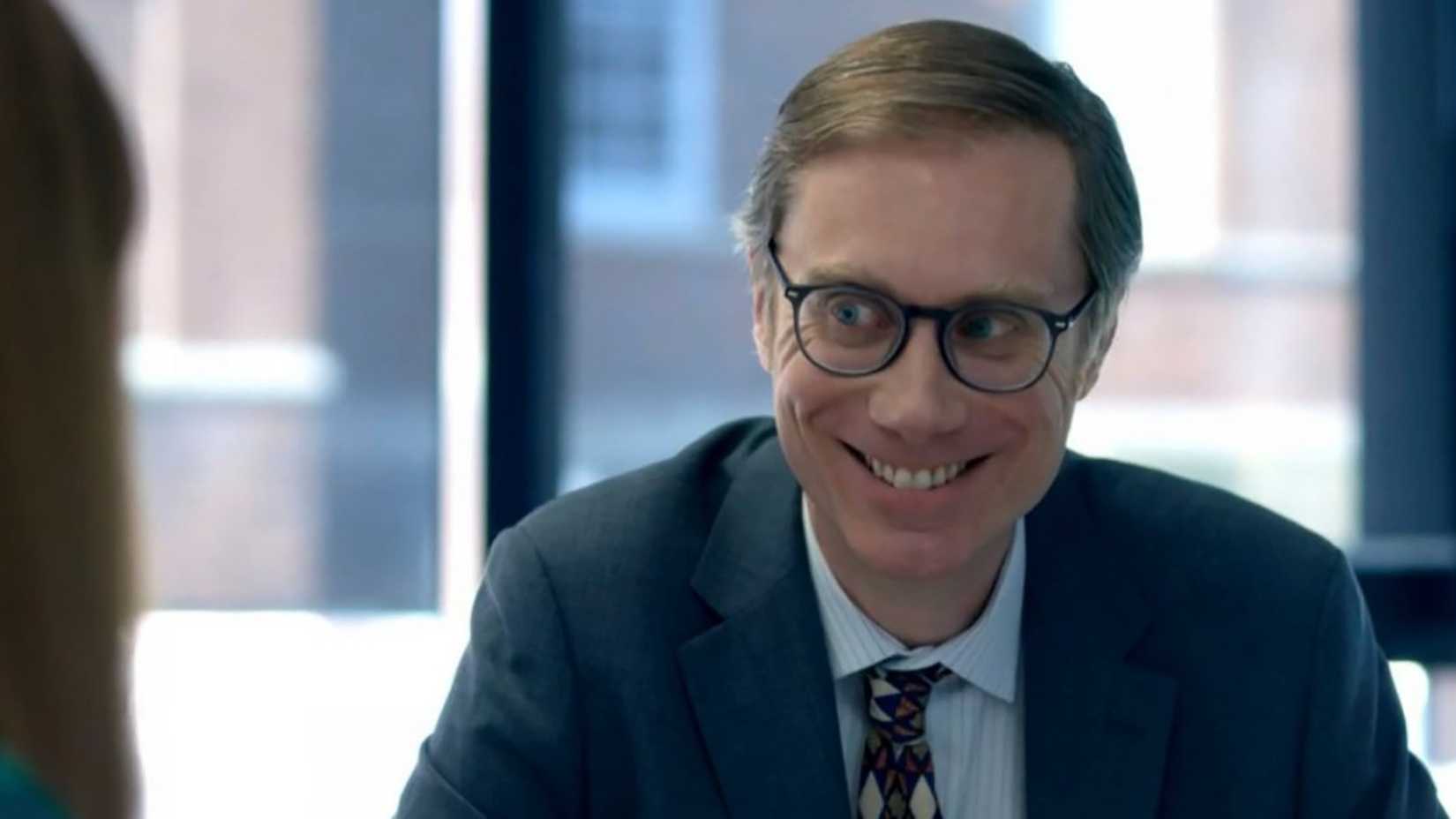 Stephen Merchant smiling in a suit in The Outlaws.