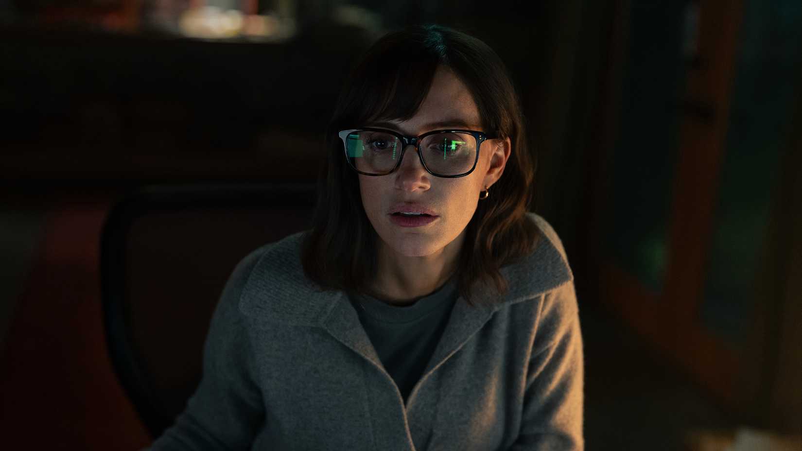 A woman sitting in front of a computer in the dark in The Savant.