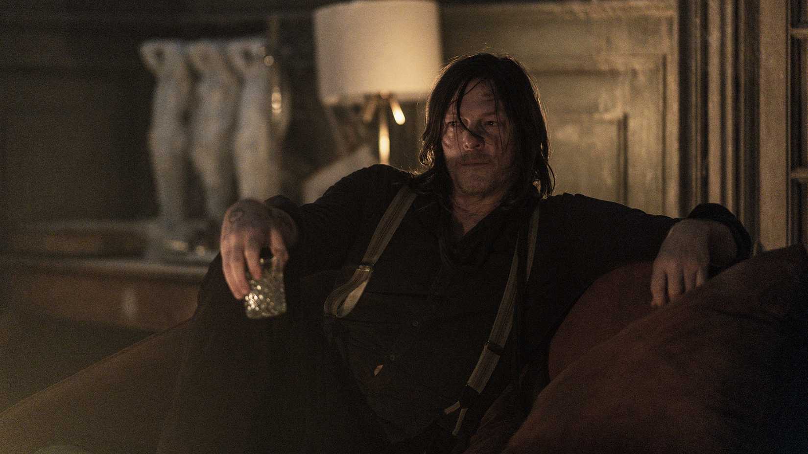 Daryl sitting back, legs crossed holding a glass of whiskey in The Walking Dead: Daryl Dixon.