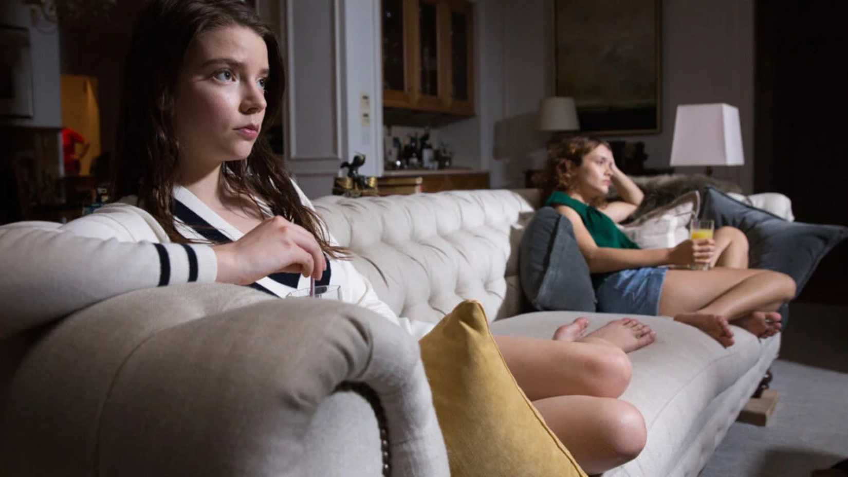 Lily and Amanda sit on a sofa in Thoroughbreds