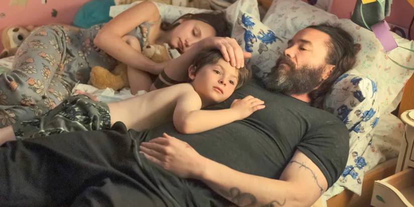 Robbie lies with his kids in bed in Task