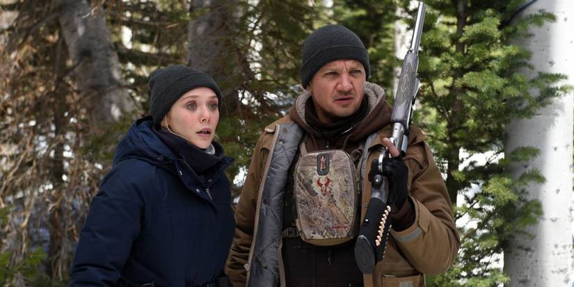Jane and Cory stand in the woods in Wind River
