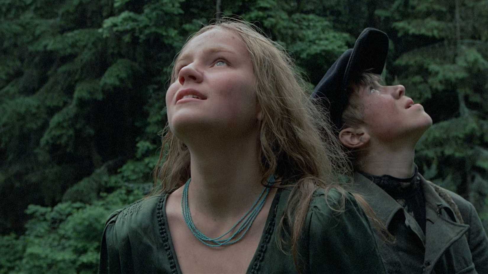 A girl and boy gaze up at the sky in Come and See
