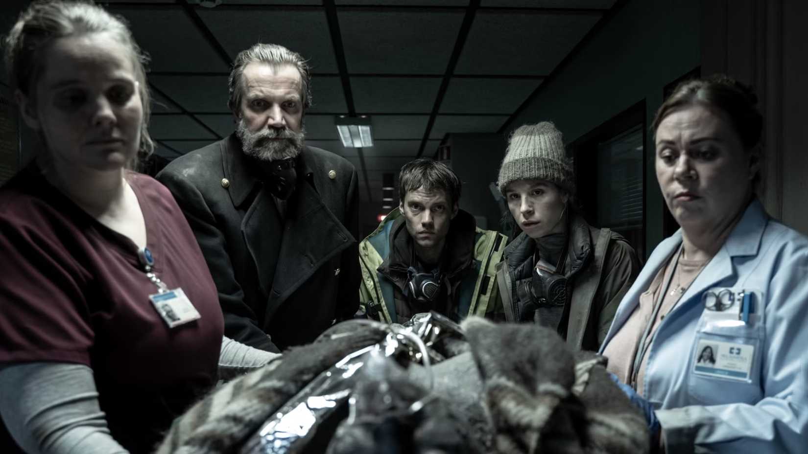 The Katla cast looking at someone in a hospital on a stretcher 