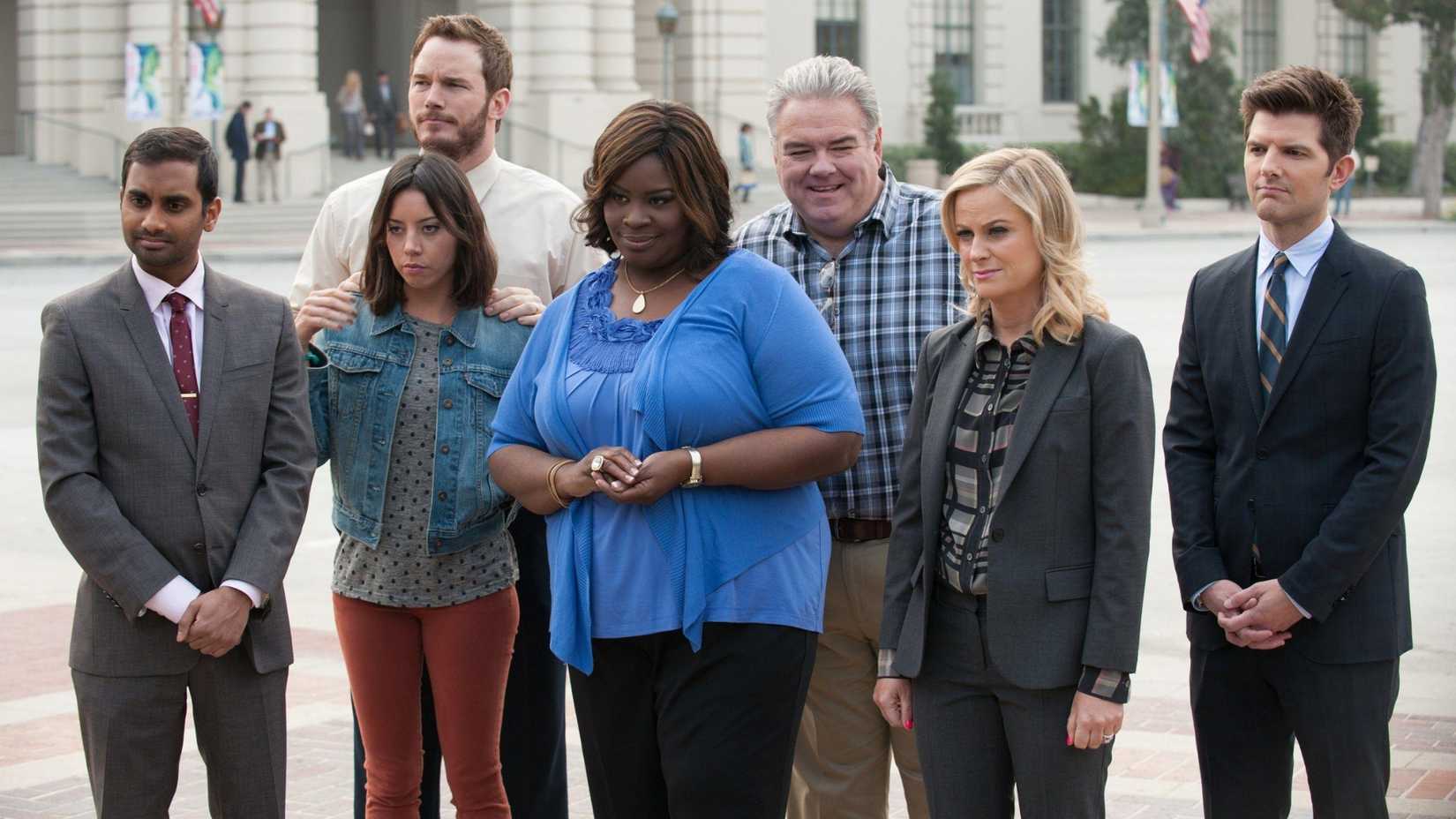 Tom, April, Andy, Donna, Jerry, Leslie, and Ben standing outside as they look at the new Founders statue for Pawnee in Parks and Recreation.
