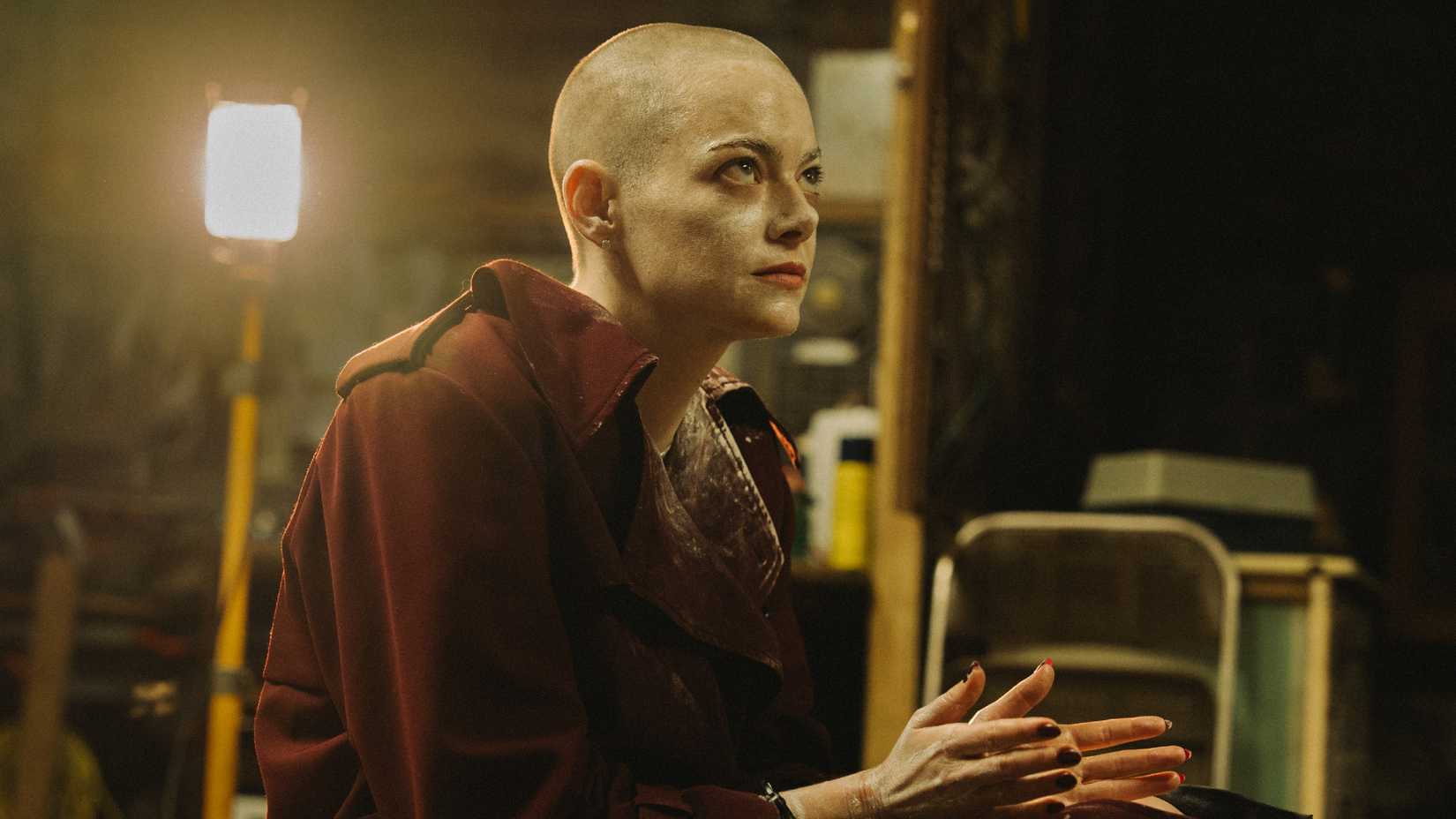 Emma Stone in Bugonia sitting on the floor with her hands cuffed