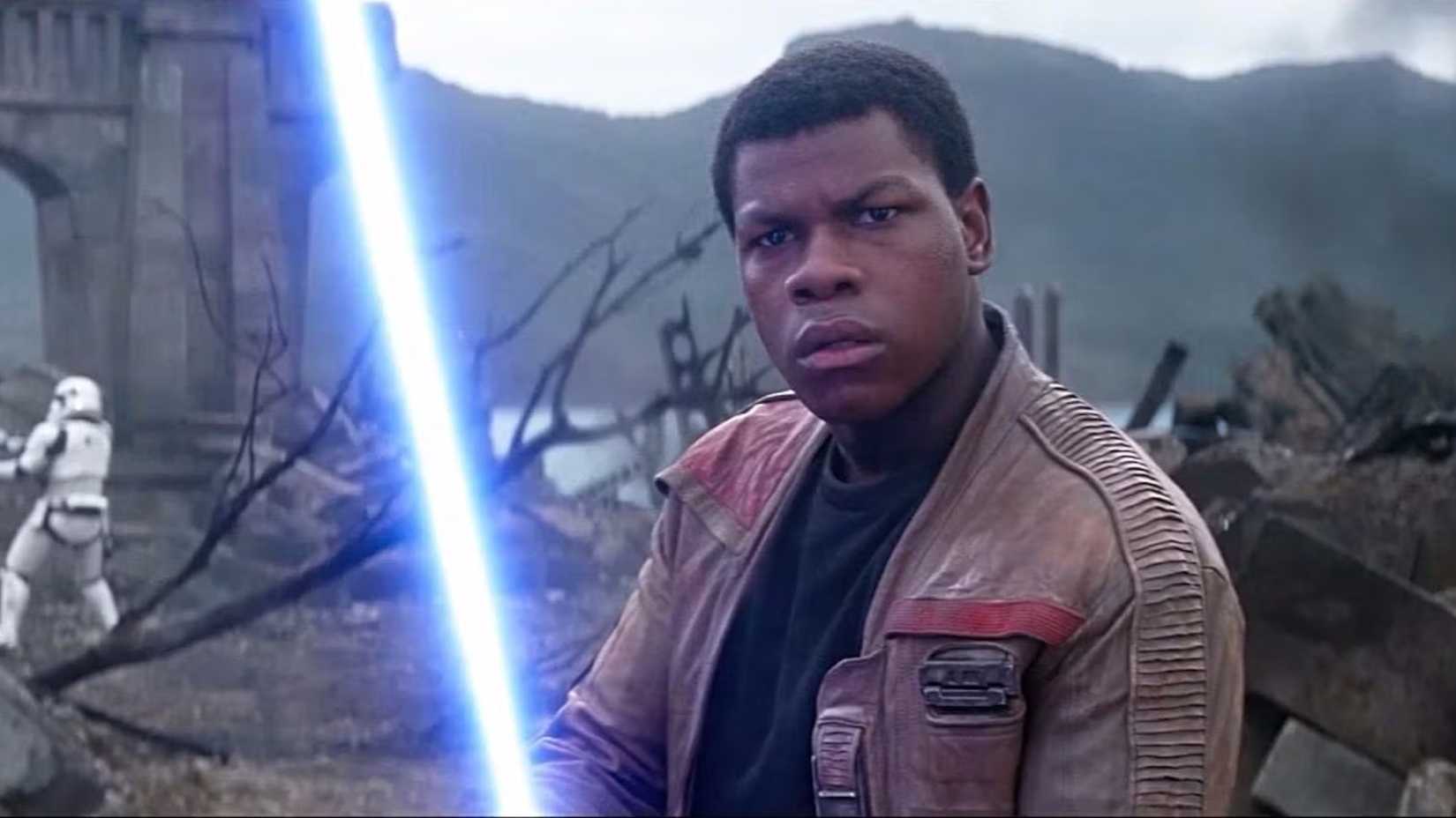 Finn in Star Wars The Force Awakens holding a blue lightsaber