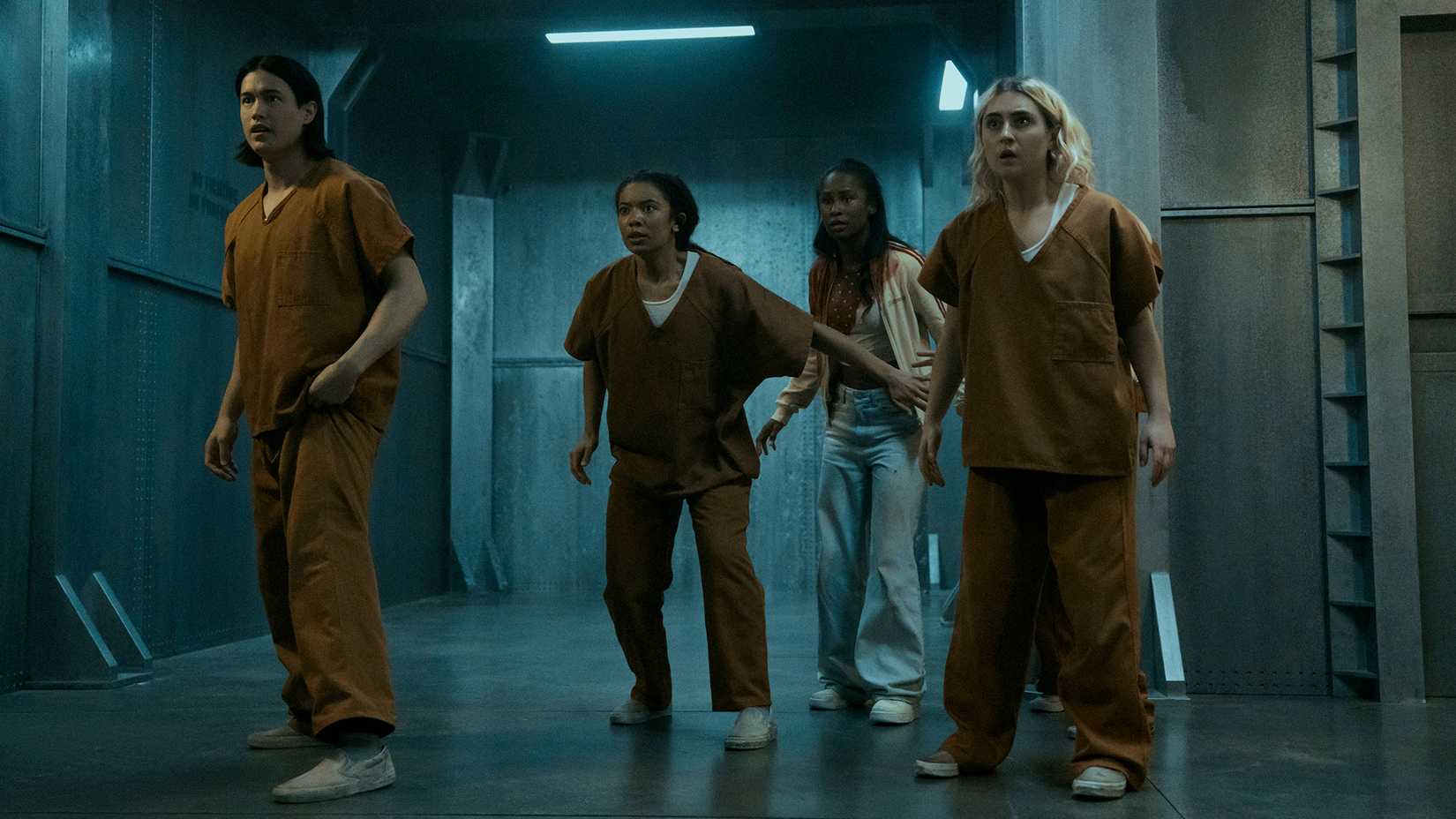 Jordan (male), Marie, Annabeth, and Emma in orange jumpsuits in Elmira in Gen V.