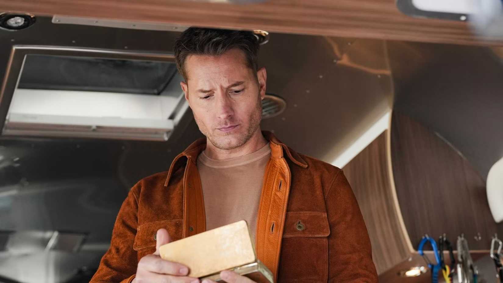 Justin Hartley in Tracker looking into a small box in an RV