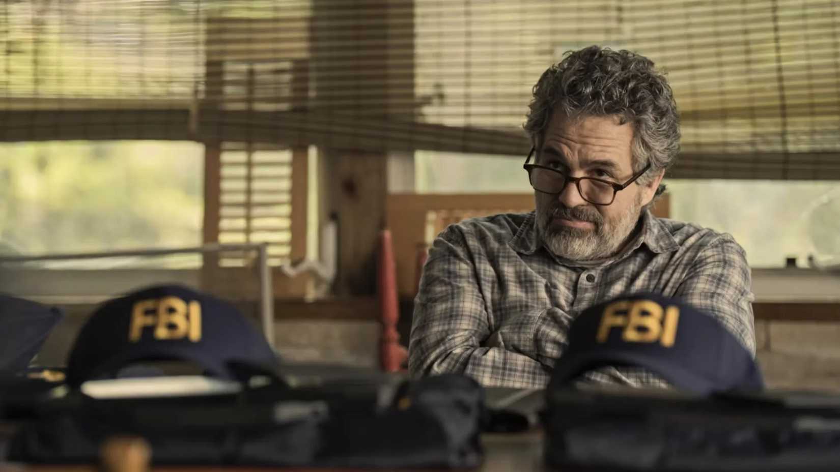 mark Ruffalo sitting in front of FBI hats in Task
