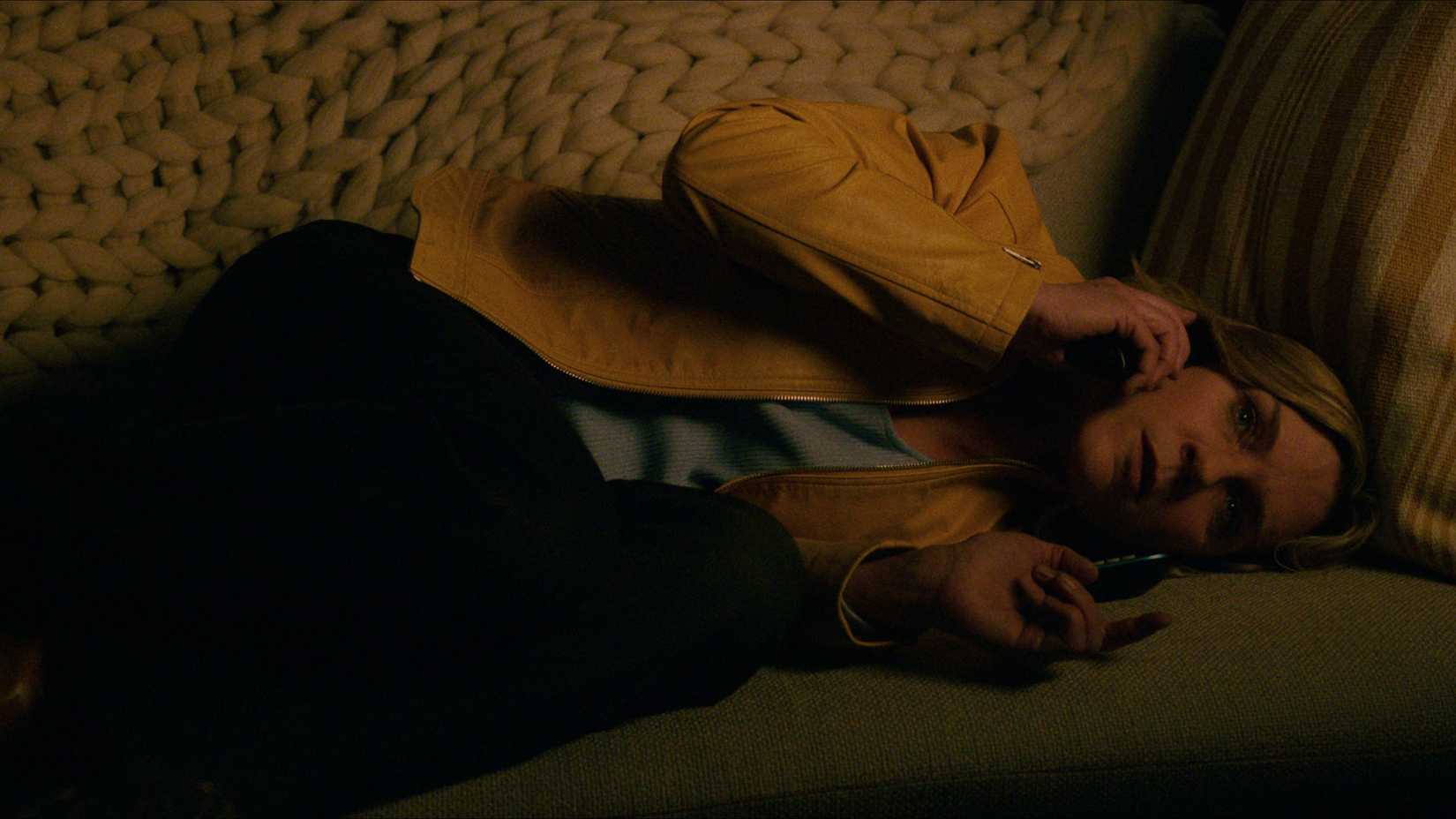 Carol lying down on the couch on the phone in Pluribus.
