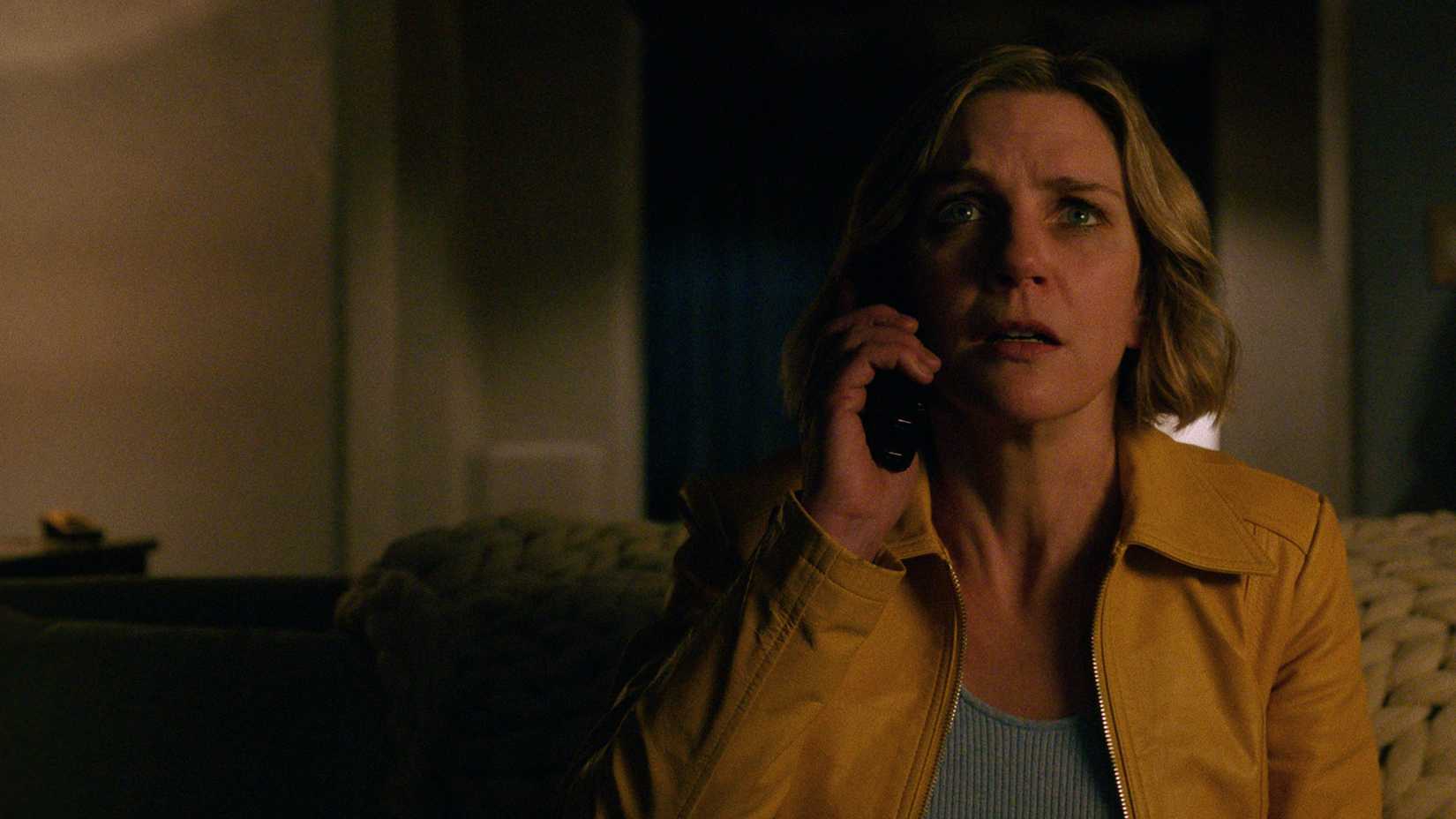 Carol on the couch on the phone looking terrified in Pluribus.