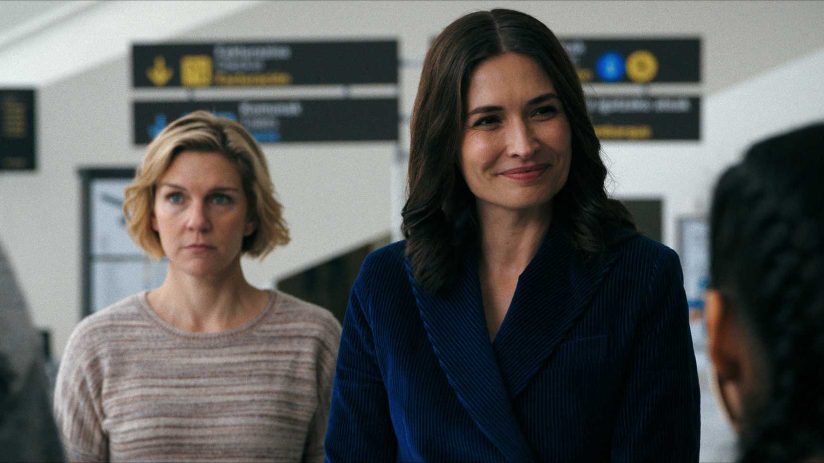 Carol behind Zosia in the airport meeting others in Pluribus.