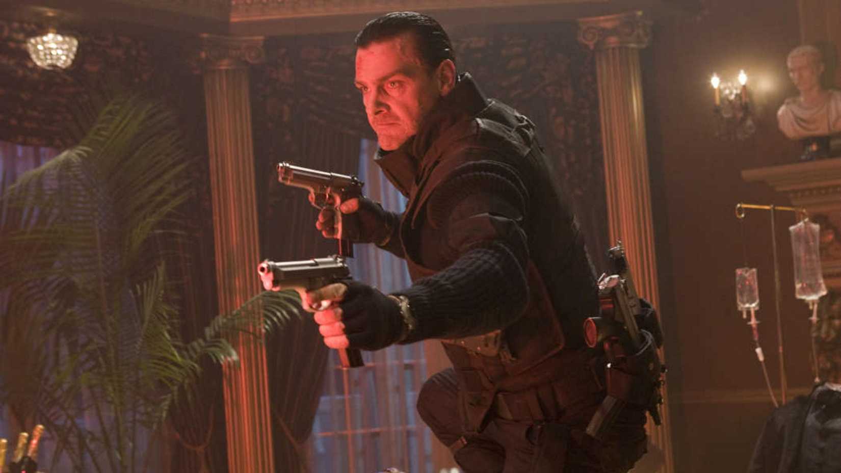 Ray Stevenson as The Punisher in Punisher: War Zone holding two pistols while wearing armor