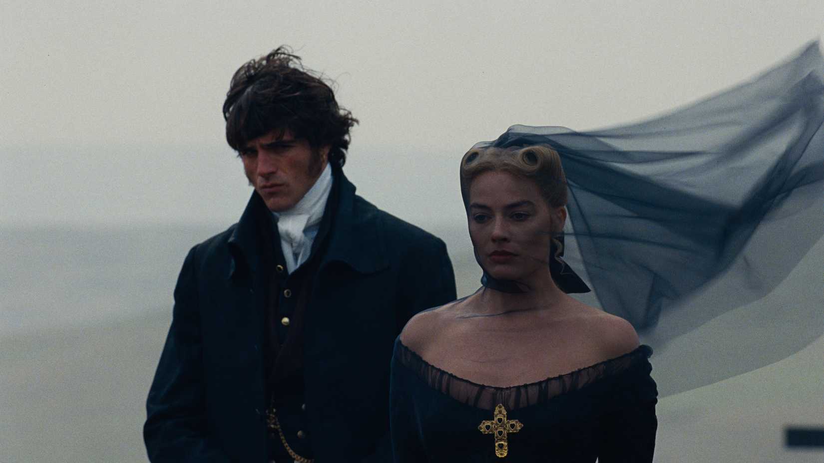 Jacob Elordi and Margot Robbie stand beside a grave in "Wuthering Heights"