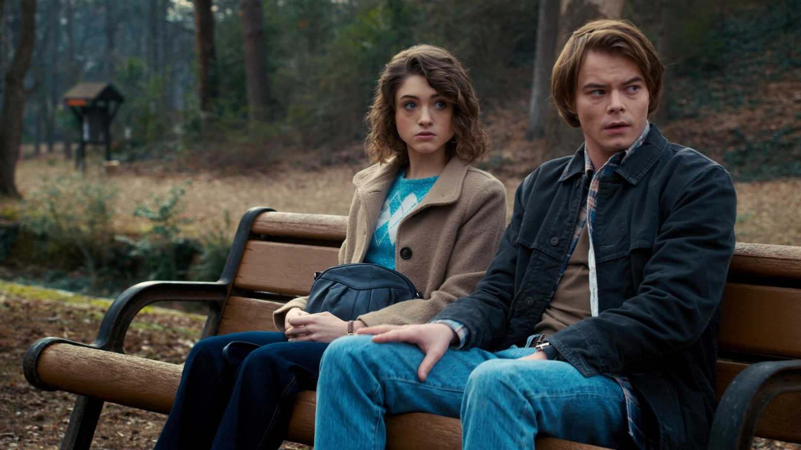 Natalia Dyer and Charlie Heaton as Nancy and Jonathan sitting on a bench in Stranger Things