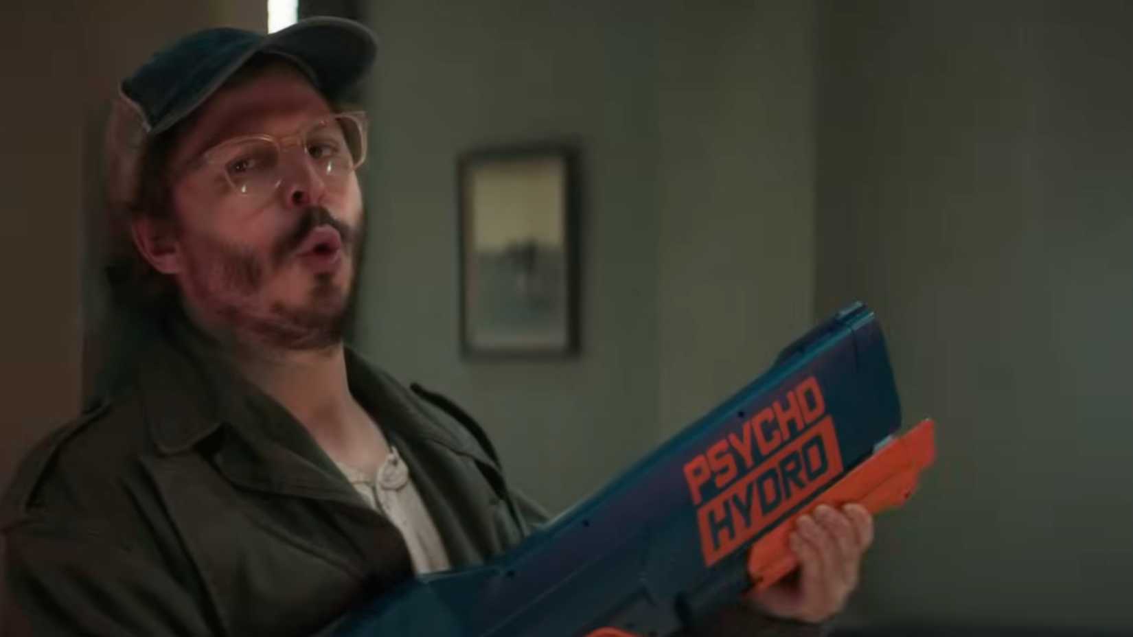 Elton holds a water gun in The Running Man