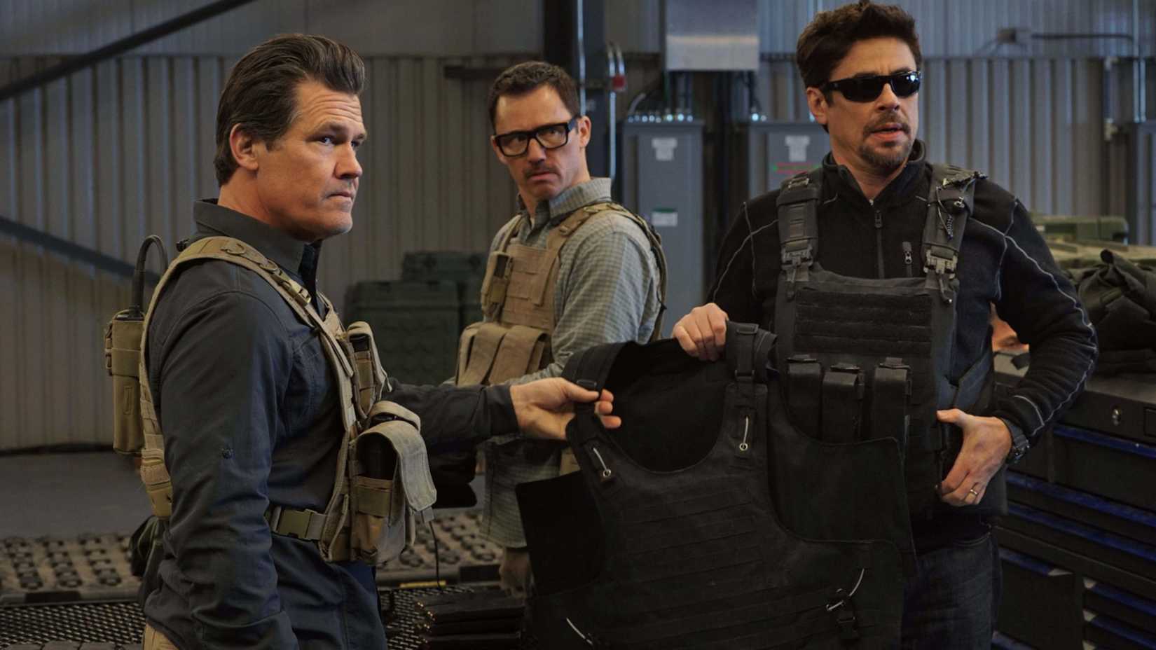 Matt and Alejandro hold a tactical vest in Sicario