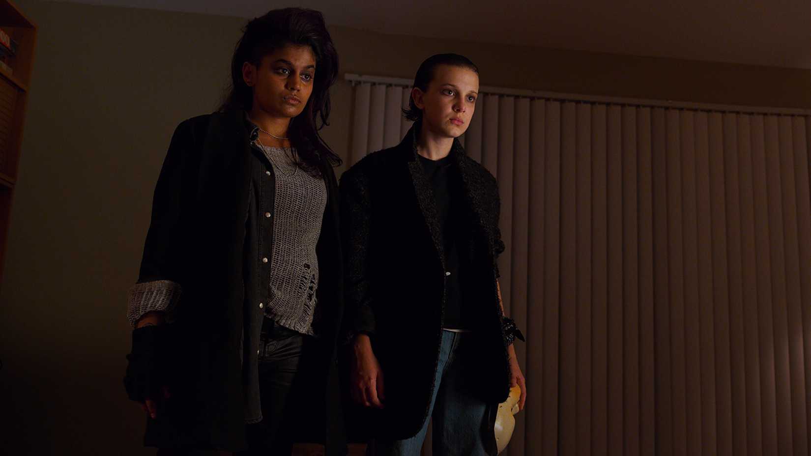 Kali and Eleven standing together in an apartment in Stranger Things.