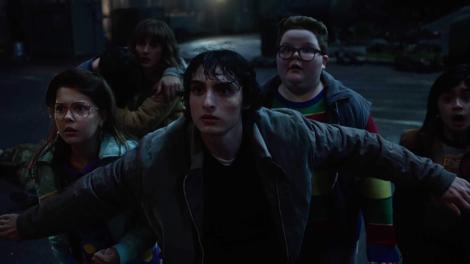 Mike standing in front of a group of kids with his arms outstretched in Stranger Things.