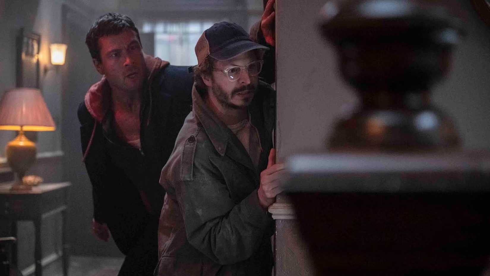 Ben and Elton hide by a wall in The Running Man