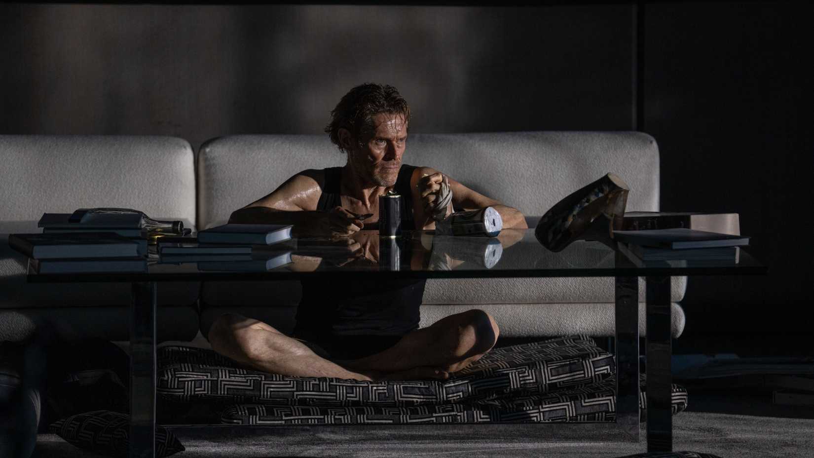 Willem Dafoe in Inside sitting at a coffee table