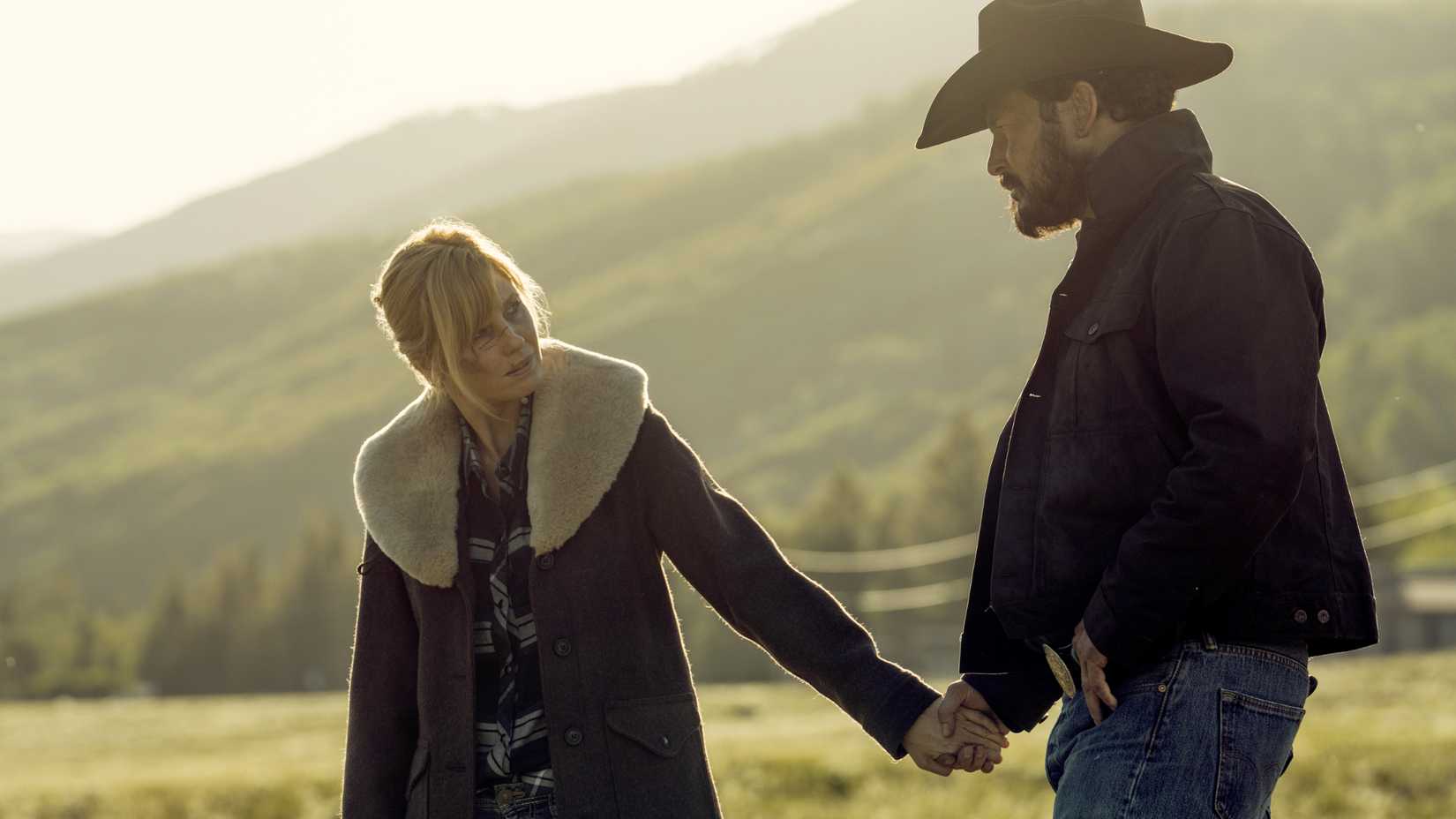 Beth and Rip hold hands in a field in Yellowstone