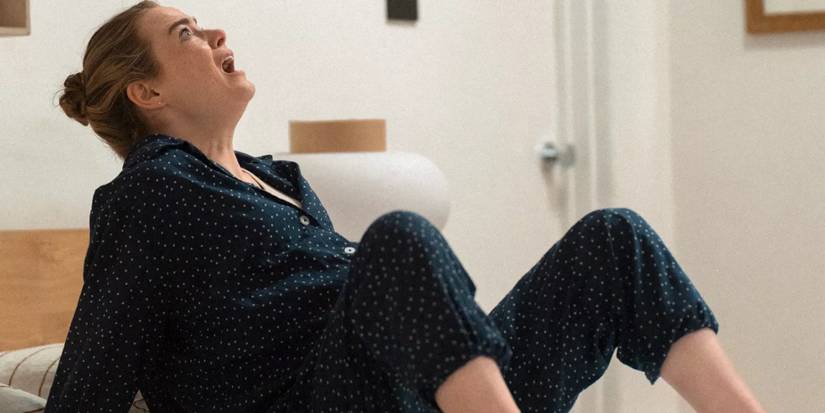 Whitney lying on the bed, panicking and looking up as Asher floats away, in The Curse.