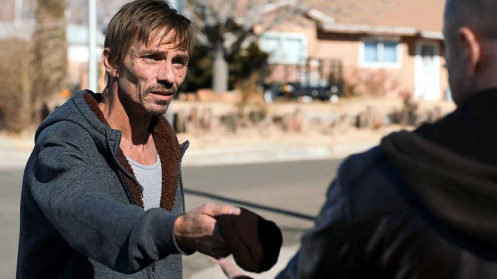 Skinny Pete in El Camino: A Breaking Bad Movie handing his beanie to someone.