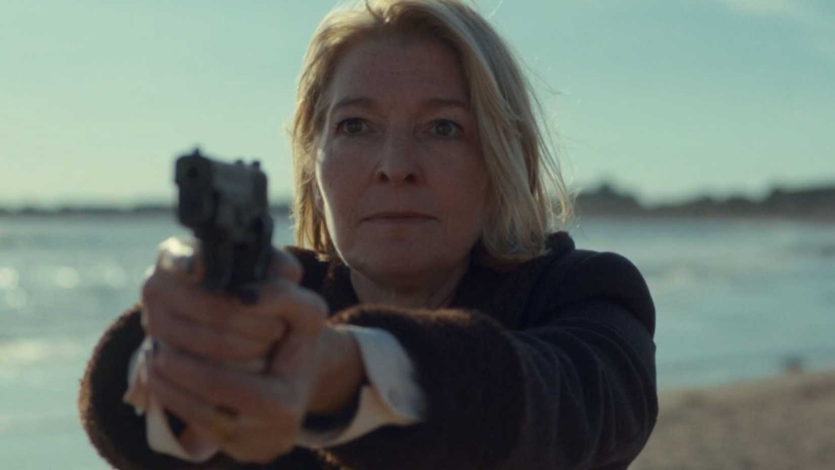 Kate aiming a gun in The War Between the Land and the Sea