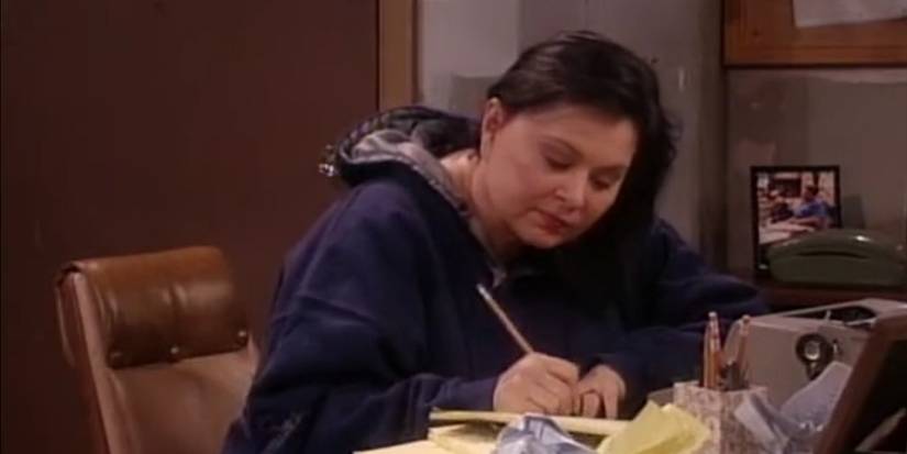 Roseanne Conner sitting at her desk and writing the end of her book in Roseanne's Season 9 finale.