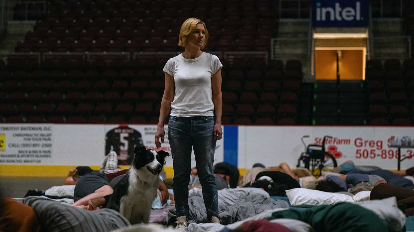 Carol standing in the middle of sleeping hive minders in a stadium in Pluribus.