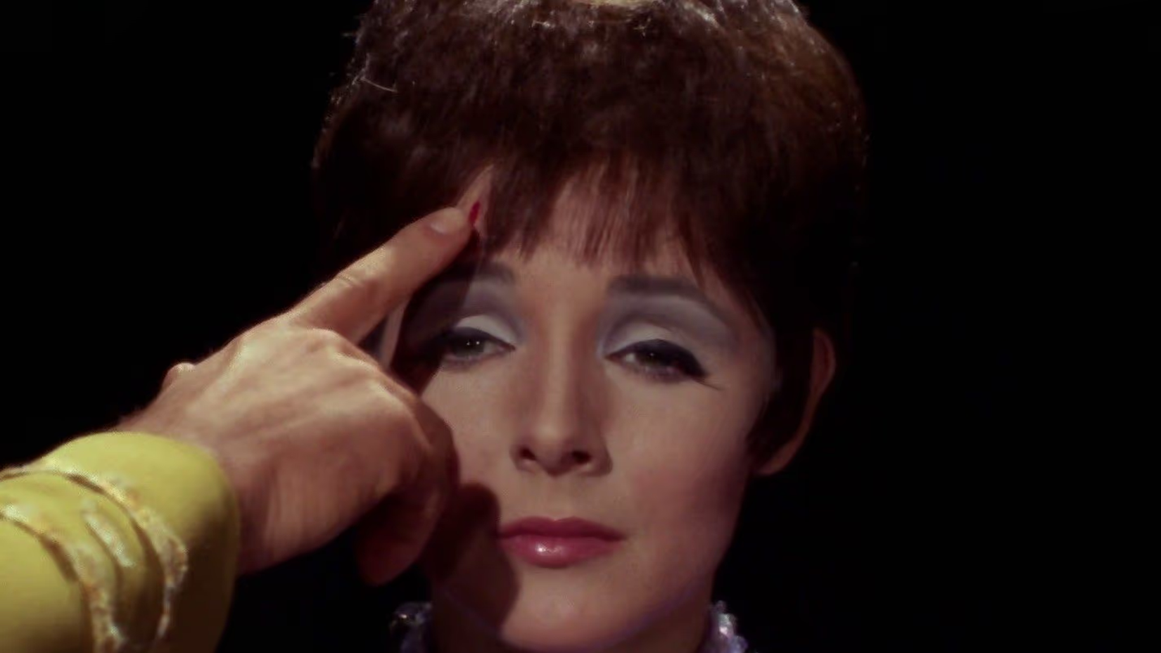 The empath from the Star Trek episode The Empath with a finger on her head