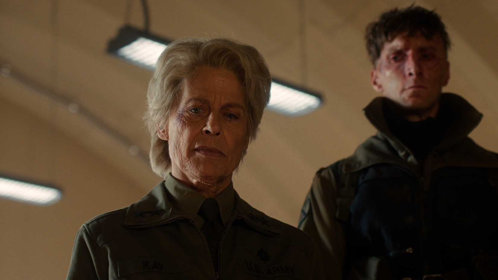 Dr. Kay looking down with a soldier behind her in Stranger Things.