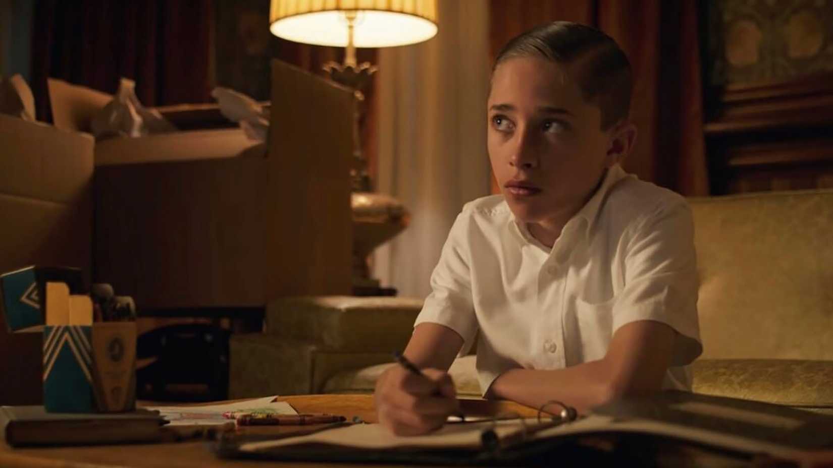 A young Henry sitting at a desk doing homework in Stranger Things.
