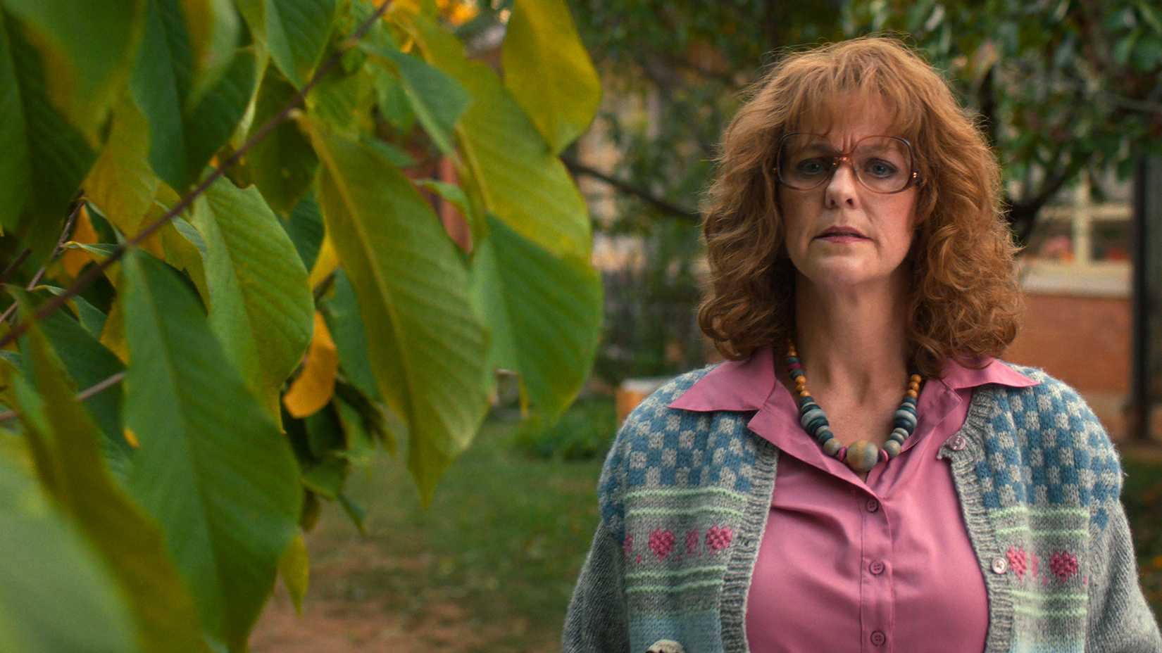 Miss Harris standing by a plant looking worried in Stranger Things.